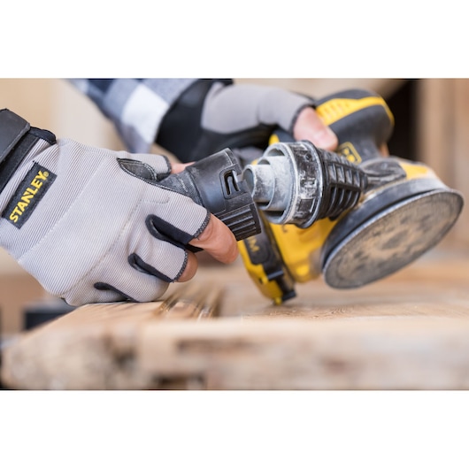 STANLEY FMCW220B photography of gloved hand operating yellow power tool on wood surface.