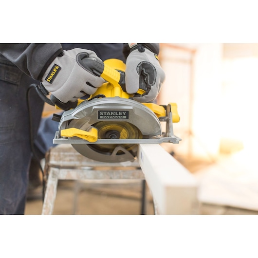 STANLEY FME301 circular saw cutting wood, close-up, with operator wearing gloves, photography.