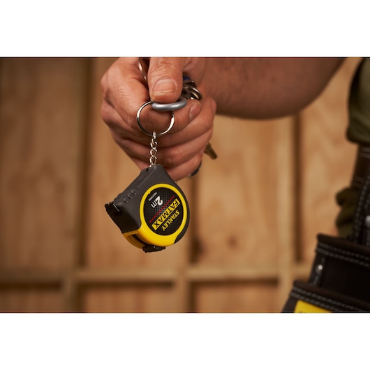 Stanley FMHT0-33856 pocket tape measure keychain held in hand, focus on yellow and black compact tool.