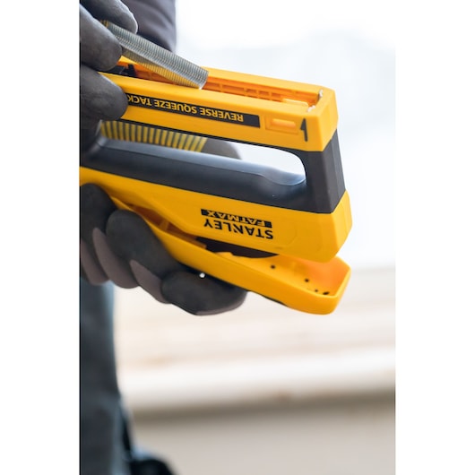 Photo of STANLEY FMHT0-80551 reverse squeeze tack yellow staple gun being loaded with staples.