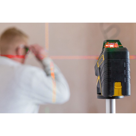 STANLEY FMHT1-77416 laser level projecting red lines, used by worker wearing safety glasses.