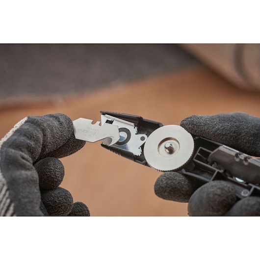 STANLEY FMHT10500-0 utility knife close-up showing blade change with gloved hands.