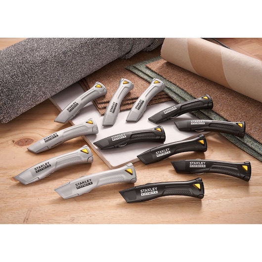 STANLEY FMHT10502-9 utility knives, grey and black, arranged on a wooden surface with carpet rolls.
