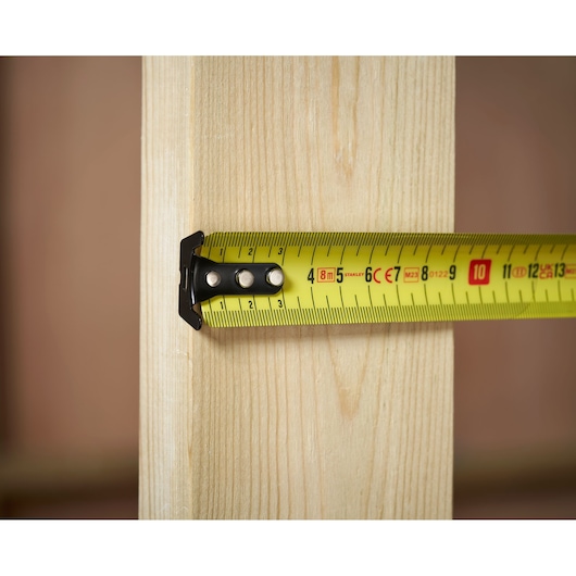 STANLEY FMHT31725-0 tape measure extended across wooden board, close-up view.