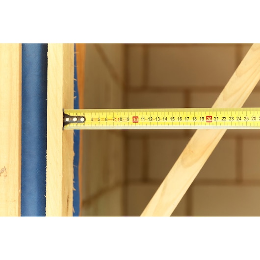 Photo of STANLEY FMHT36142-0 yellow tape measure extended across wooden beams, close-up view.