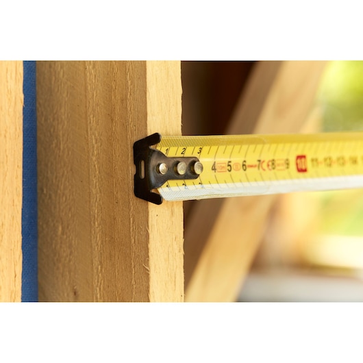 STANLEY FMHT36142-0 tape measure extended on wood beam, close-up angle, yellow metric markings.