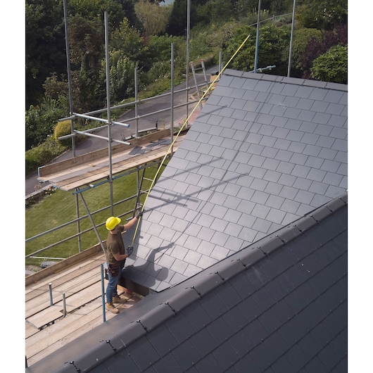 Photo of STANLEY FMHT38217-0 tape measure in use on a rooftop construction site with scaffolding.