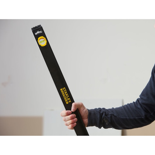 Photo of STANLEY FMHT42559-1 spirit level, black body with yellow vial, being held in hand.