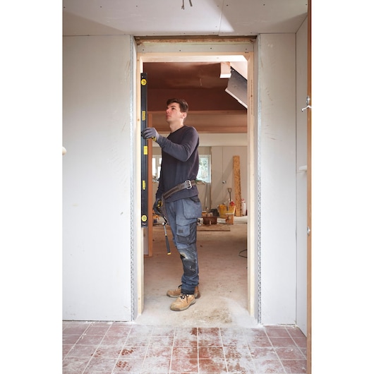 Photo of STANLEY FMHT42559-1 spirit level used by a worker in doorway, construction site background.