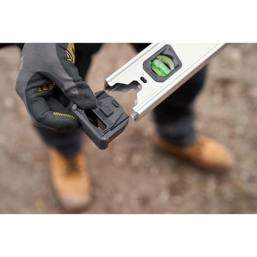 Photo of STANLEY FMHT43671-1 level tool with detachable black module held by gloved hand.