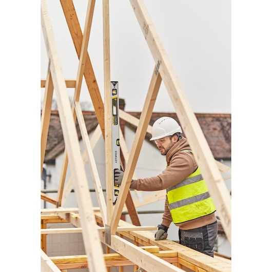 STANLEY FMHT43675-1 spirit level held vertically by construction worker checking wooden frame.