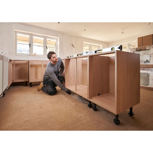 STANLEY FMHT43676-1 spirit level on cabinets during installation, side angle, in a bright kitchen under construction.