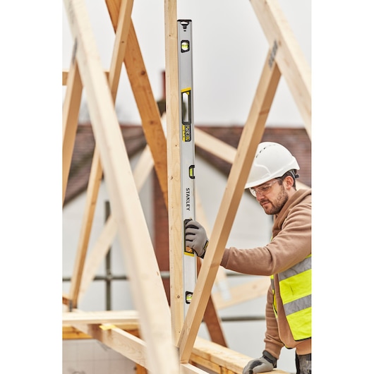 STANLEY FMHT43676-1 spirit level in use by a construction worker on a wooden frame building site.