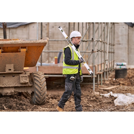 Photo of STANLEY FMHT43676-1 spirit level held by worker at muddy construction site.