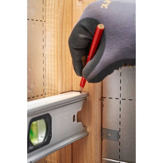 STANLEY FMHT43677 photography of a gloved hand marking wood with pencil beside spirit level, close-up angle.