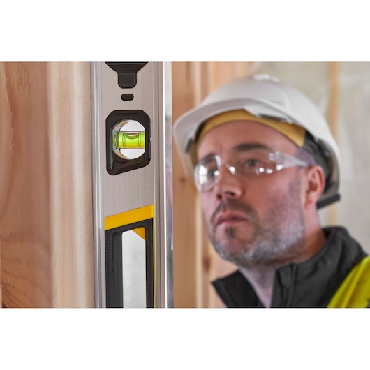 STANLEY FMHT43677 spirit level close-up with yellow and black details, used on a wooden frame.