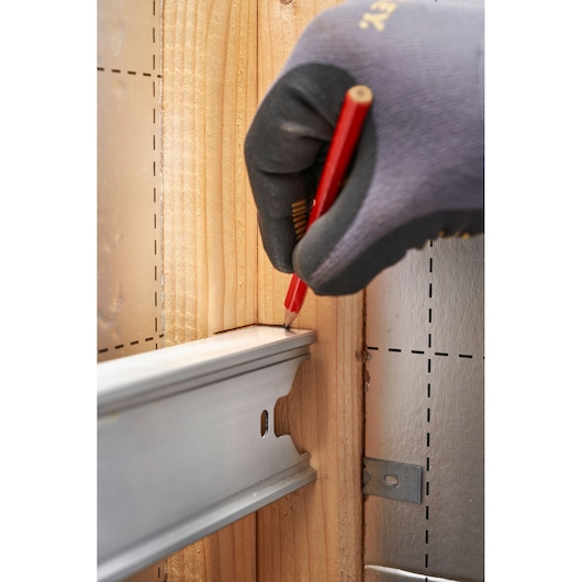 Stanley FMHT43679-1 photography of gloved hand marking wood near metal rail in construction setting.