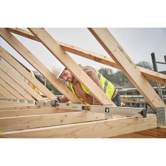 STANLEY FMHT43680-1 spirit level used on wooden beams in construction site, shown in side view.