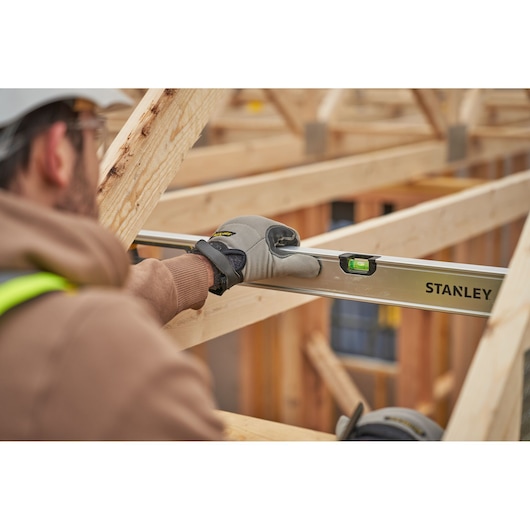 Stanley FMHT43680-1 spirit level used by worker in construction, focusing on level tool and wooden frame.