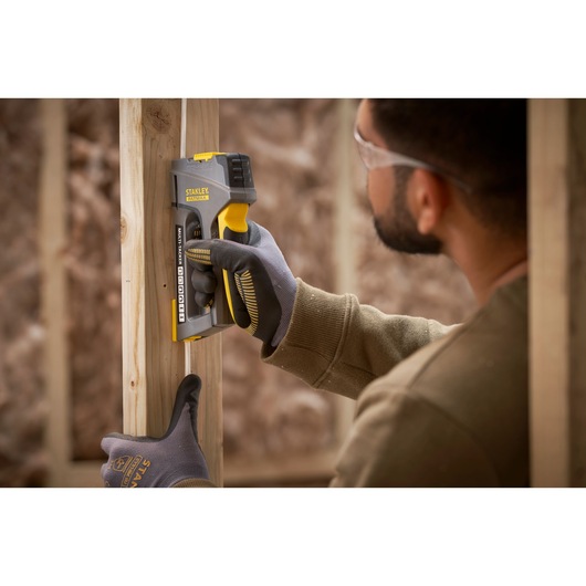 STANLEY FMHT6-70868 staple gun in use on wooden frame, close-up photography of tool and gloved hand.