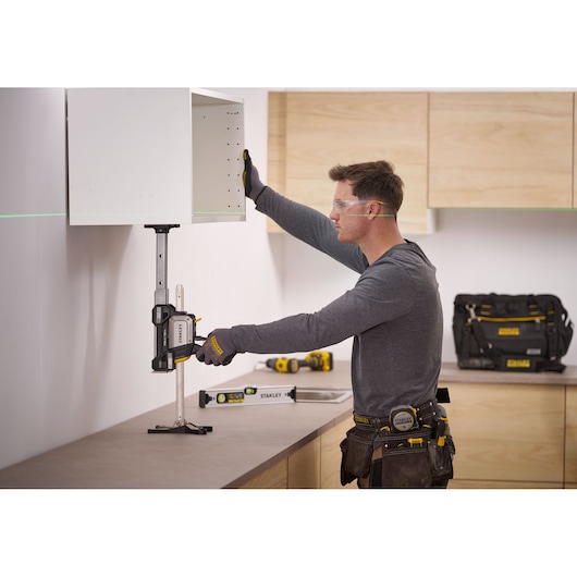 STANLEY FMHT83554-1 cabinet support clamp in use, holding a wall cabinet during installation, side angle.