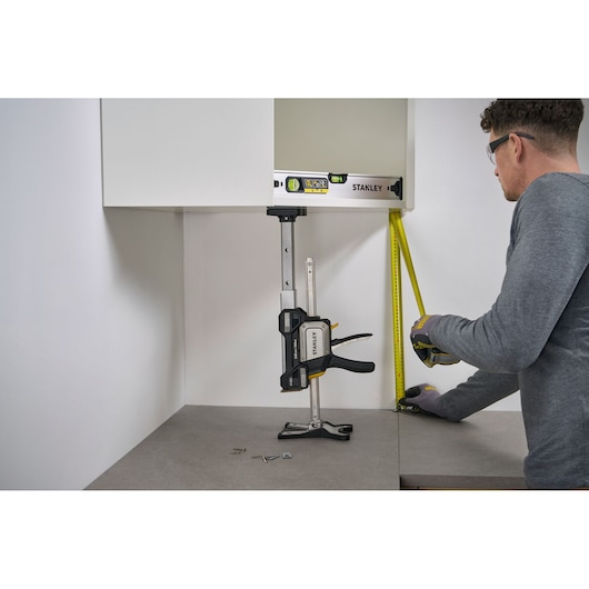 STANLEY FMHT83554-1 clamp being used for cabinet installation, shown with level and tape measure on a countertop.