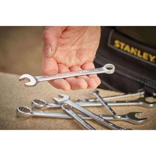 STANLEY FMMT13030-0 combination wrench held in hand, several wrenches on tabletop, close-up photography.