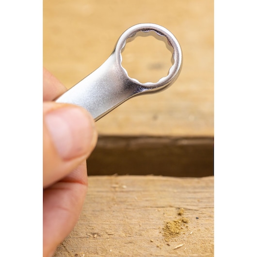 STANLEY FMMT13031-0 box-end wrench close-up held by hand, silver finish, photography on wood surface.