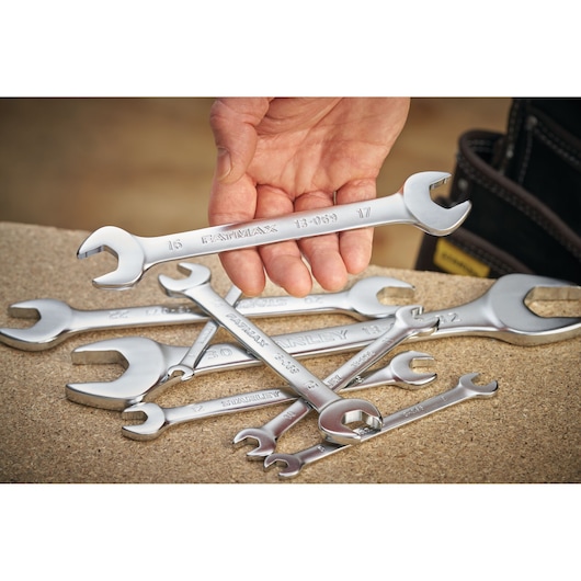STANLEY FMMT13074-0 photography of silver open-end wrenches, one held in hand, others scattered on workbench.
