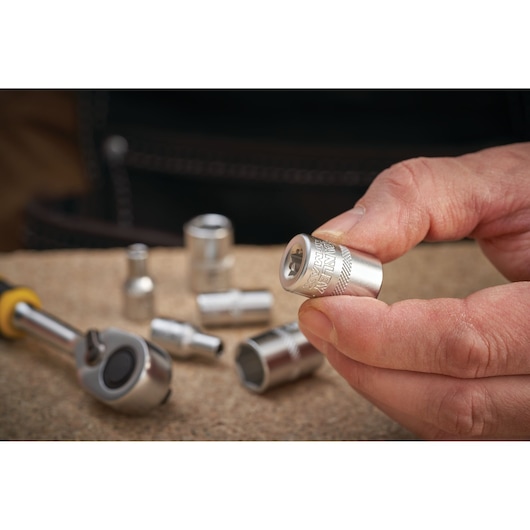 Photo of STANLEY FMMT17185-0 socket held in hand, with ratchet and other sockets on work surface.