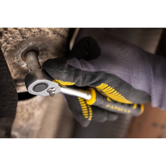 Photo of STANLEY FMMT17185-0 ratchet wrench in gloved hand tightening a bolt, close-up view.