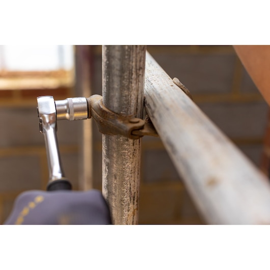 STANLEY FMMT17239-0 ratchet wrench in use tightening metal clamp on scaffolding, close-up photography.
