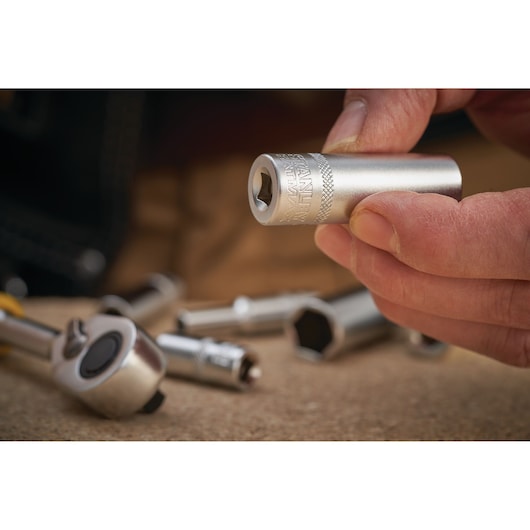 Photo of STANLEY FMMT17339-0 socket held in hand, silver finish, with ratchet tool and other sockets blurred in background.