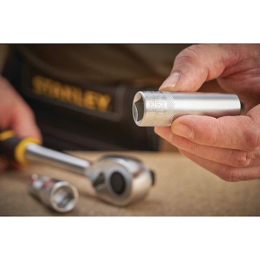 STANLEY FMMT17967-0 socket held in hand, close-up with ratchet wrench on work surface.