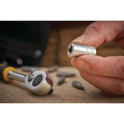 STANLEY FMMT18007-0 socket tool held by hand, with ratchet and bits on tabletop, close-up photo.