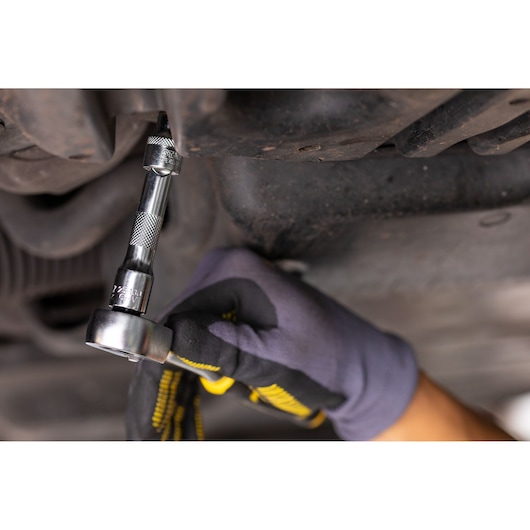 STANLEY FMMT25123-0 ratchet wrench used on bolt, close-up, automotive repair, gloved hand.