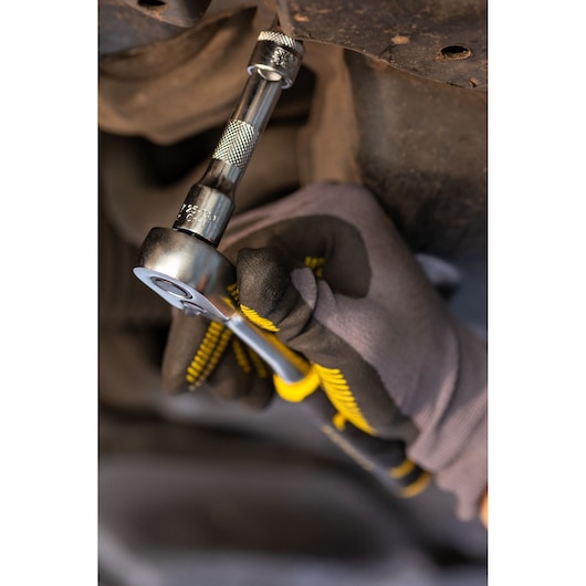 STANLEY FMMT25123-0 ratchet wrench in use, close-up, held by gloved hand under vehicle.