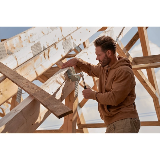 STANLEY hammer used to secure metal bracket to wooden roof frame during construction, outdoor scene.