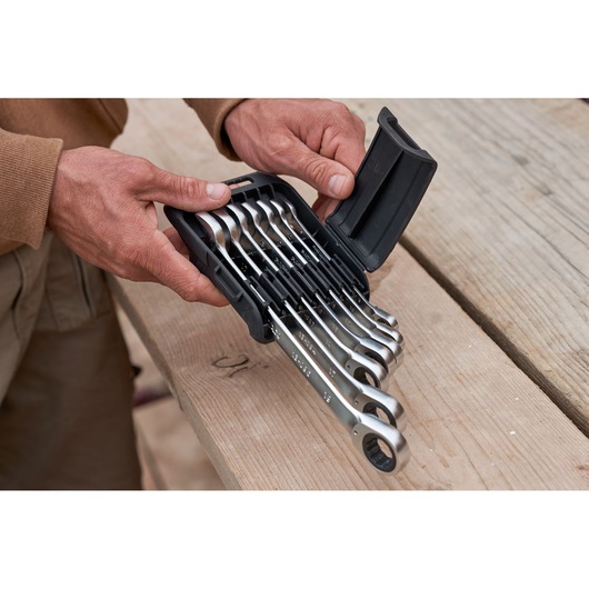 STANLEY FMMT82848-0 7-piece reversible ratcheting wrench set in case held by hands, photo on wooden surface.