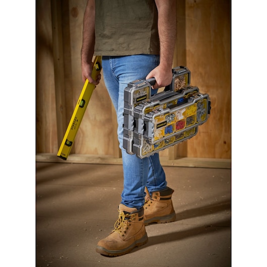 Photo of STANLEY FMST1-75779 stackable organizer set carried by worker with level tool, boots, and jeans.