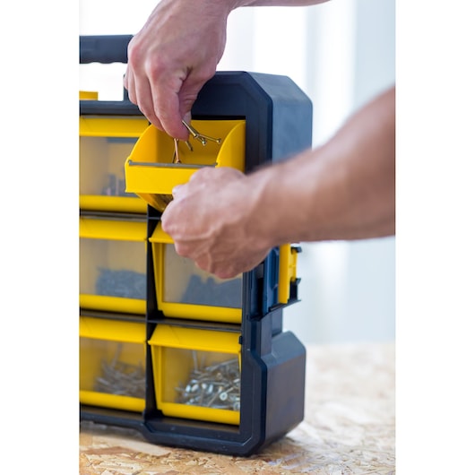 Photo of STANLEY FMST81077-1 organizer with yellow pull-out bins holding various hardware, hand accessing top bin.