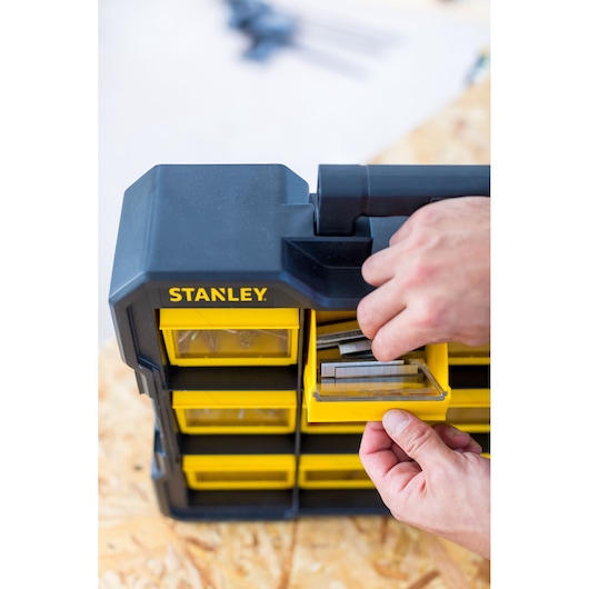 STANLEY FMST81077-1 organizer with yellow drawers, hand opening a drawer with metal fasteners.