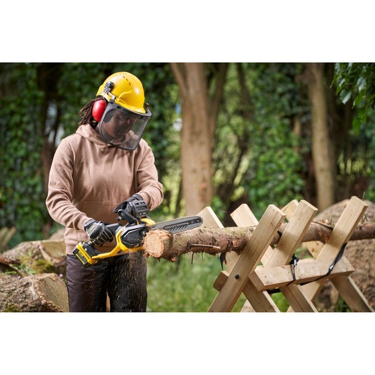Photo of STANLEY SFMCCS730B chainsaw in use cutting a log outdoors, with operator wearing safety gear.