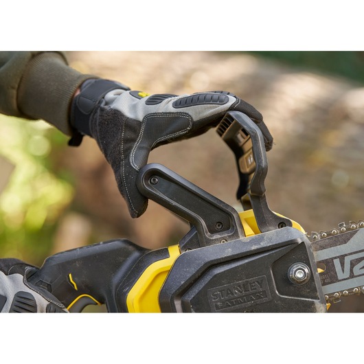 STANLEY SFMCCS730B chainsaw detail with gloved hand on handle outdoors.