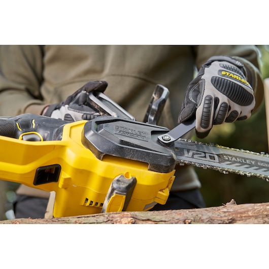 Stanley SFMCCS730B chainsaw close-up with gloves adjusting chain outdoors.