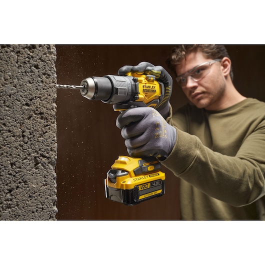 Photo of STANLEY SFMCD726B cordless drill in use, drilling into concrete.