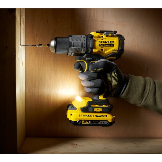 STANLEY SFMCD726B cordless drill in use drilling into wood, side angle, yellow and black design.