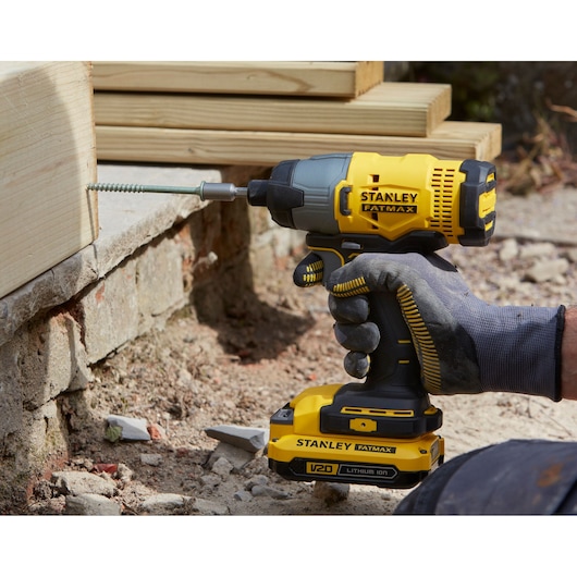 STANLEY SFMCF800C2K cordless impact driver in use driving screw into wood, close-up angle outdoors.