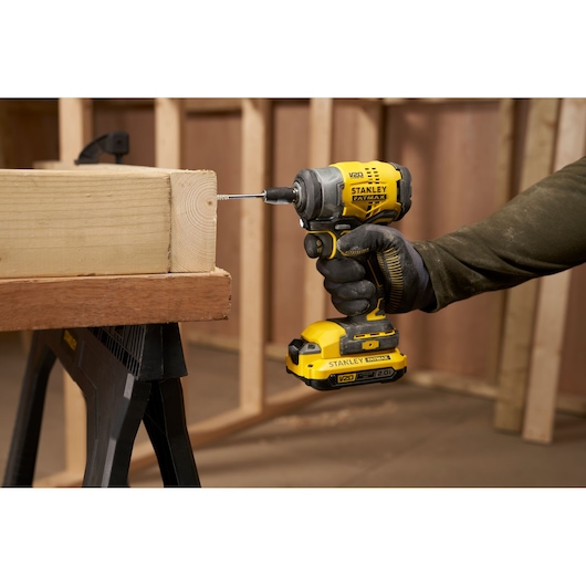 Photo of STANLEY SFMCF910B cordless impact driver being used to drive a screw into wood at a construction site.