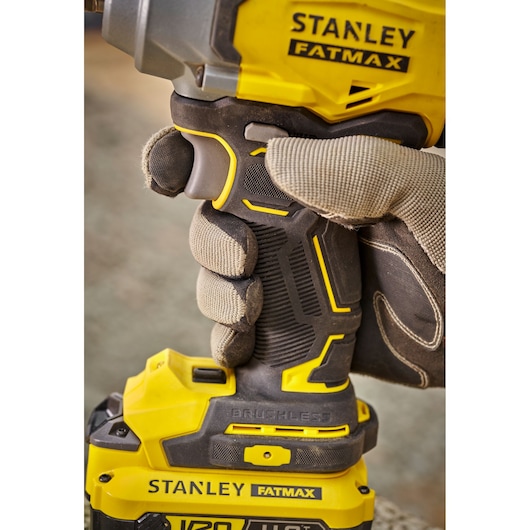 Photo of STANLEY SFMCF920B impact driver held by a gloved hand, showing yellow and black ergonomic grip.